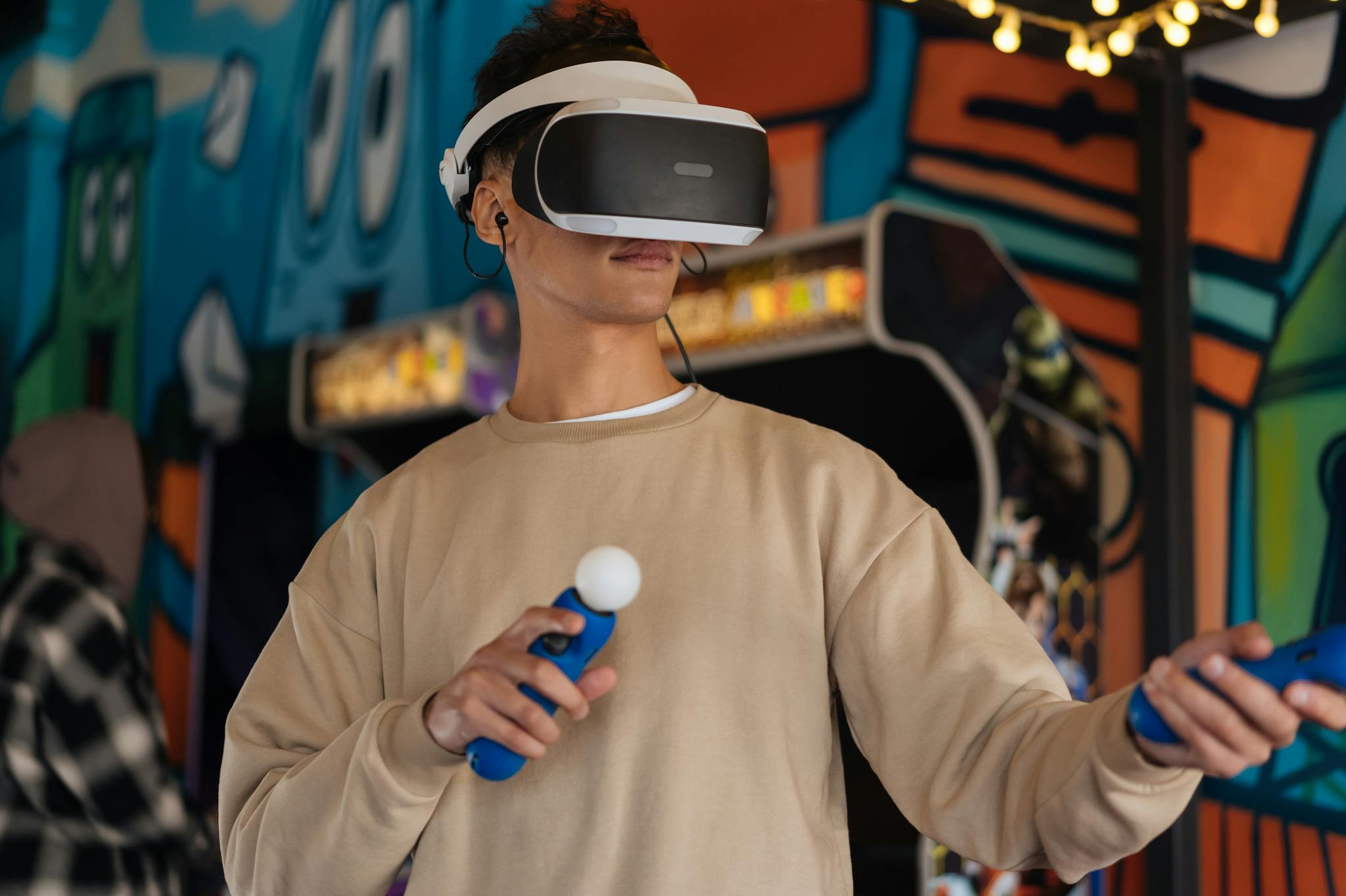 An adult man experiencing a virtual reality game with VR goggles and controllers in a vibrant setting.